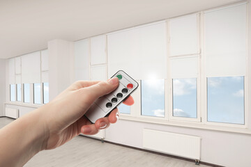Woman using remote to control blinds in room, closeup