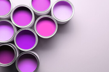 Cans with paint in shades of violet on white background, top view. Space for text