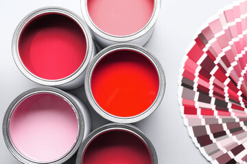 Cans with paint in shades of red and color palette on white background, top view