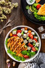 Grilled sliced chicken breast and Greek salad on wooden table	