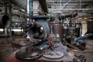Disassembled industrial valve used for maintenance and repair. The metal housing, bolts, and internal components are laid out on a workbench, showing detailed mechanical parts.