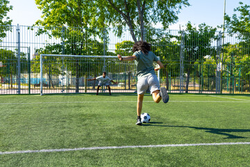 Female soccer player taking a penalty kick during a sunny day