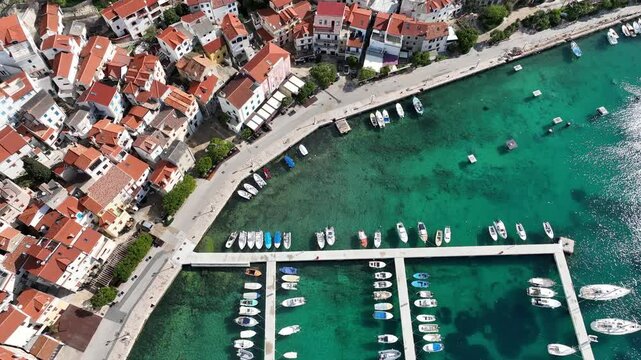 Baska beach and coastline with crystal-clear turquoise water, marina boats, city street, sunny summer mood captured from drone view on Krk Island. Baska vacations town in Adriatic sea