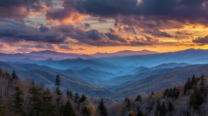 Obraz premium Colorful sunset over smoky mountain range with glowing clouds and layered forest landscape