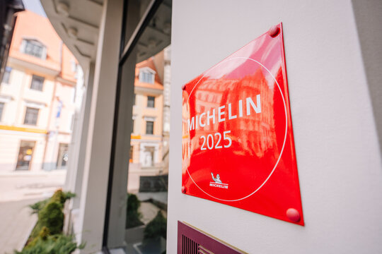Angled view of a red “MICHELIN 2025” plaque on a wall outside a restaurant, signifying prestigious culinary recognition..