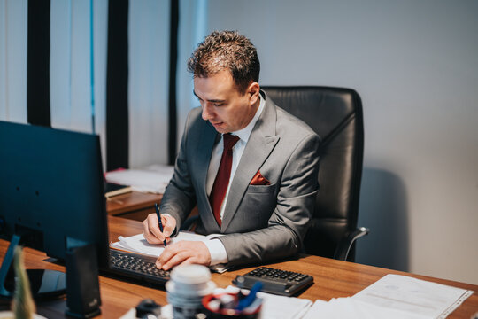 Professional man wearing a suit is concentrating on his work at a modern office. The image conveys professionalism, focus, and corporate dedication, emphasizing business responsibilities and