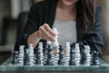Asian businesswoman playing chess to plan business and market probability by using chess in work. Leadership concept.
