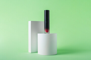 Mockup of black blank thin tube - mascara, lip gloss, gel, eyeliner, oil, etc. Cosmetic package with stylish props on green background. 