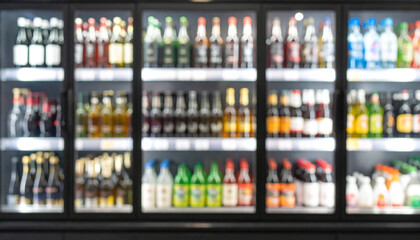 Blurred background of supermarket fridge with bottles of beverages on shelves. Glass showcase.