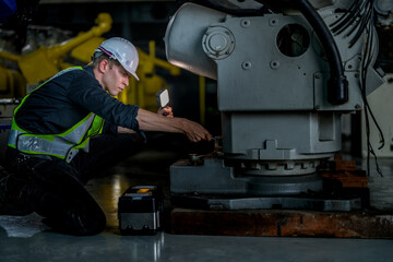 male engineer workers maintenance automatic robotic arm machine in a factory. worker checking and...