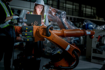 team engineers inspecting on machine with smart tablet. Worker works at heavy machine robot arm. The welding machine with a remote system in an industrial factory. Artificial intelligence concept.
