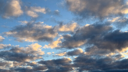Luminous sunset clouds in a vibrant sky reflecting warmth and tranquility over a peaceful horizon of soft blue and dusky grey tones
