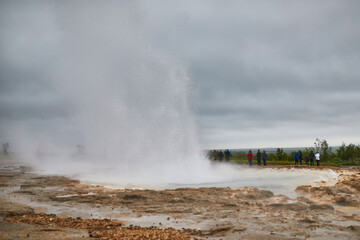 Famous Strokkur geyser erupting on a foggy rainy day in Iceland.