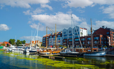 Scenic view of a marina on a sunny day, featuring a variety of yachts docked along the pier in Gdansk, Poland. Picturesque waterfront scene.