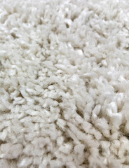 Closeup abstract white fluffy fur fabric carpet texture background.Selective focus.