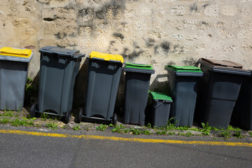 Des poubelles en plastique alignées dans une rue dans un village