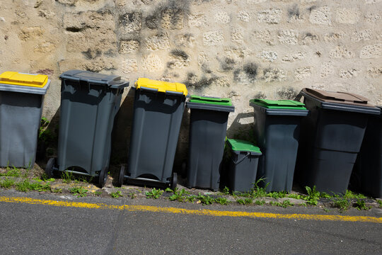 Des poubelles en plastique align&eacute;es dans une rue dans un village