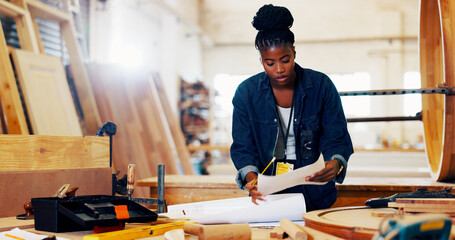 Carpentry, industry and plans with black woman in workshop for manufacturing or production process. Design, lumber and paper with carpenter in woodworking studio for craftsmanship or manual labor © peopleimages.com