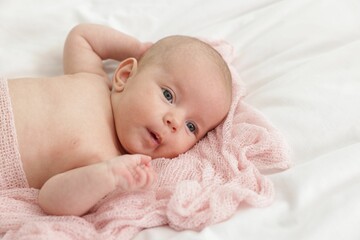 Cute little baby lying on bed at home
