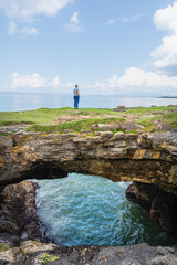 Obraz premium Beeindruckende Fairy Bridges mit Tullan Strand im Hintergrund und eine Frau die darüber geht