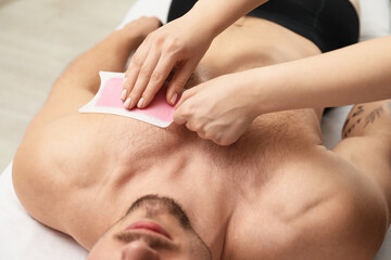 Young man undergoing wax epilation in salon, closeup