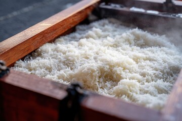 Perfectly steamed white rice in a wooden container ready to be served at a traditional outdoor gathering