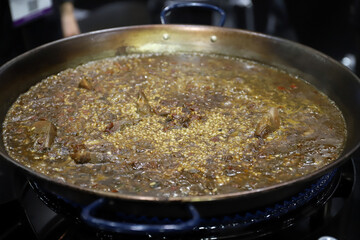 elaboración de arroz caldoso en una paellera que esta en el fogón cocinándose
