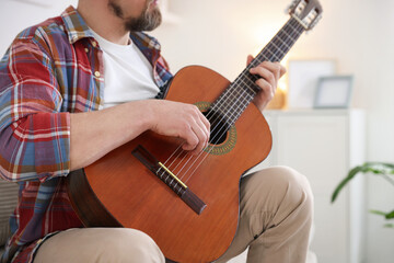 Man playing acoustic guitar at home, closeup