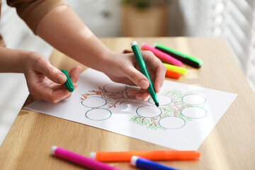 Woman drawing family tree at wooden table, closeup