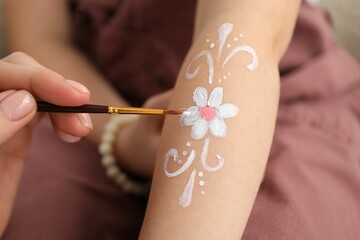 Animator drawing flower on girl's arm indoors, closeup