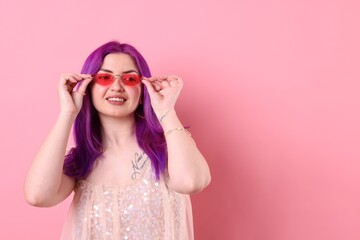 Beautiful woman with bright purple hair and tattoo in Latin on pink background. Space for text