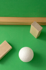 Still life with wooden blocks and a a plastic foam ball on green background	