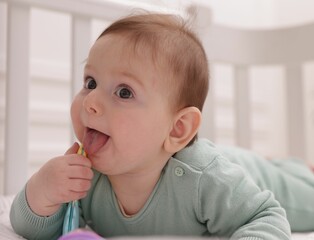 Cute little baby with rattle toy in crib at home