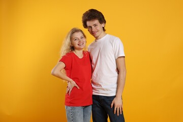 Fototapeta premium Young woman and man wearing blank t-shirts on orange background. Mockup for design