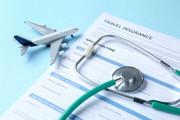 Medical tourism. Travel insurance application form, stethoscope and plane model on light blue...