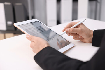 Electronic signature. Man using stylus and tablet at white table, closeup
