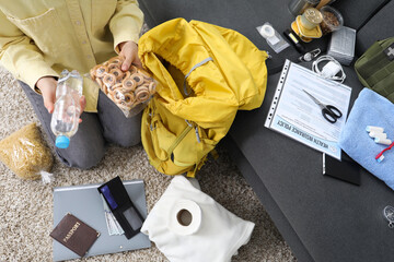 Survival kit. Woman packing different emergency supplies on floor indoors, above view