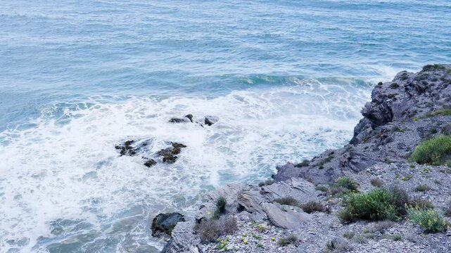 Rocky Coastline of Calblanque Natural Park in Murcia, Spain with Foamy Waves Crashing on Jagged Shore under Overcast Lighting