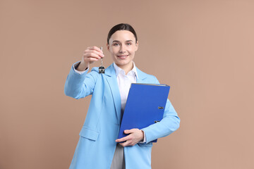 Real estate agent holding key with house shaped keychain and folder on beige background