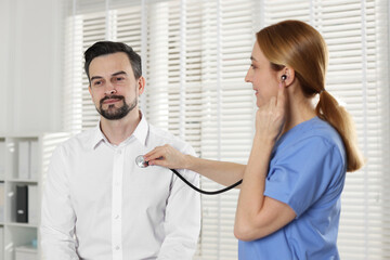 Cardiologist with stethoscope listening patient's heartbeat in hospital