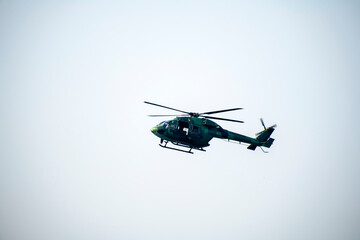 Silhouette Helicopter is flying over isolated blue sky 