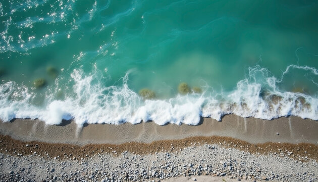 Aerial view of turquoise ocean waves crashing on rocky beach shoreline with copy space