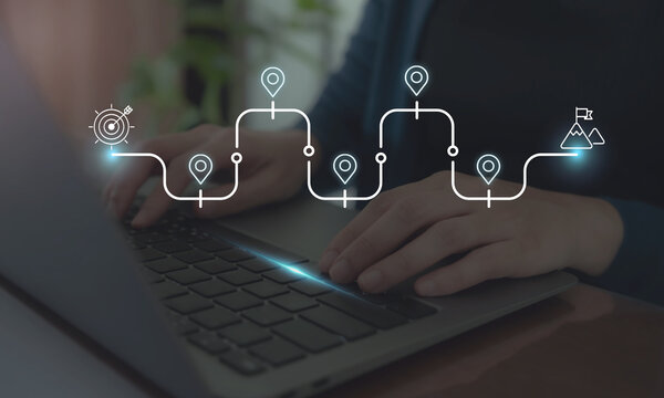 Business and Project Roadmap Concept. Typing on a laptop with roadmap overlay representing steps in a project or strategic planning process. Waypoint icons and ends with   goal achievement.