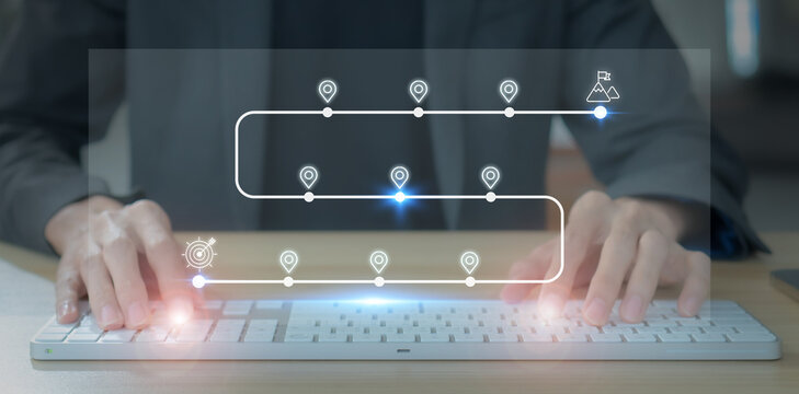 Business and Project Roadmap Concept. Typing on a computer keyboard with roadmap overlay representing steps in a project or strategic planning process. Waypoint icons and ends with goal achievement.