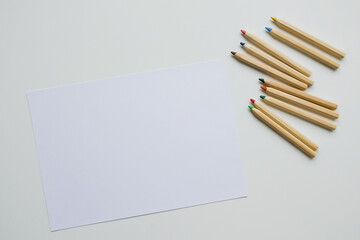 Blank sheet with multicolored pencils on white surface