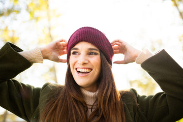 Happy woman adjusting her beanie outdoors