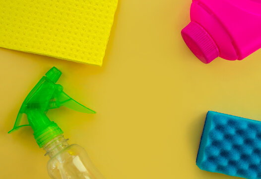Cleaning. Flat lay Bottles with cleaning product and sponges on a yellow background, empty space in the center.