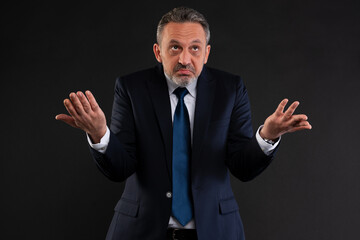 Businessman shrugging with raised hands in confusion.
