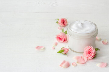 Closeup of pink roses essence skin care cream with flowers and petals