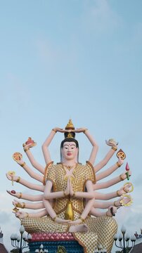 Colorful statue of Guanyin, the Goddess of Mercy and Compassion in East Asian Buddhism with eighteen arms in Wat Plai Laem temple on Koh Samui island in Thailand. Vertical orientation